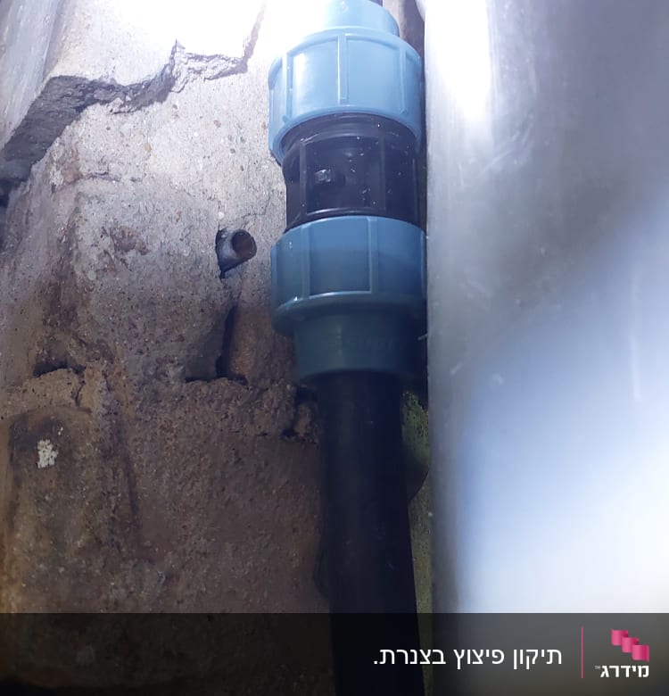 צינור שחור עם מחבר פלסטיק כחול בקיר בטון